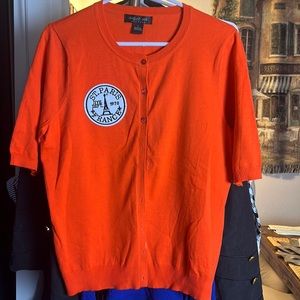 Orange short sleeve sweater with a patch on front